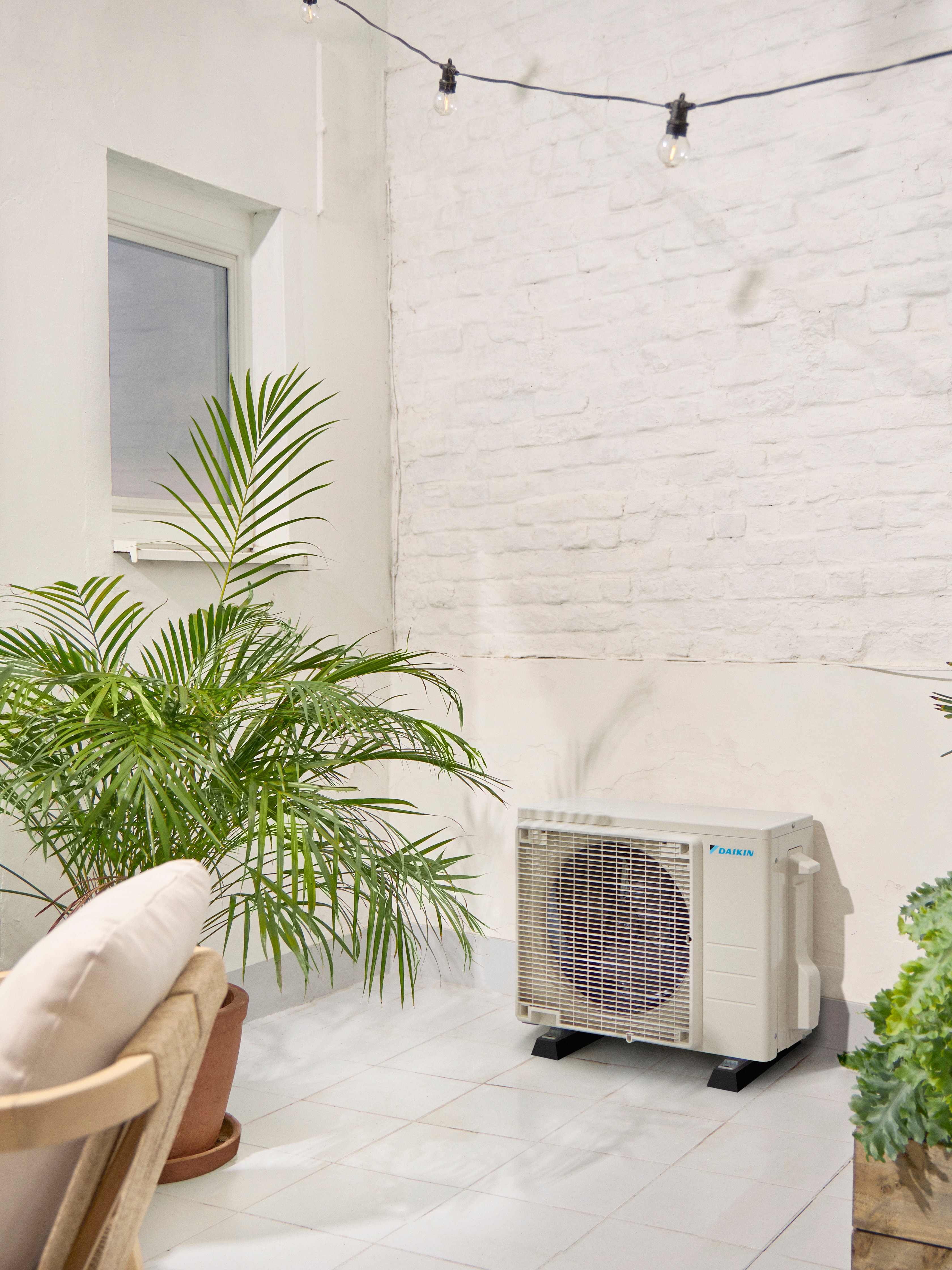 Vonkajšia jednotka Daikin na bielej terase s rastlinou