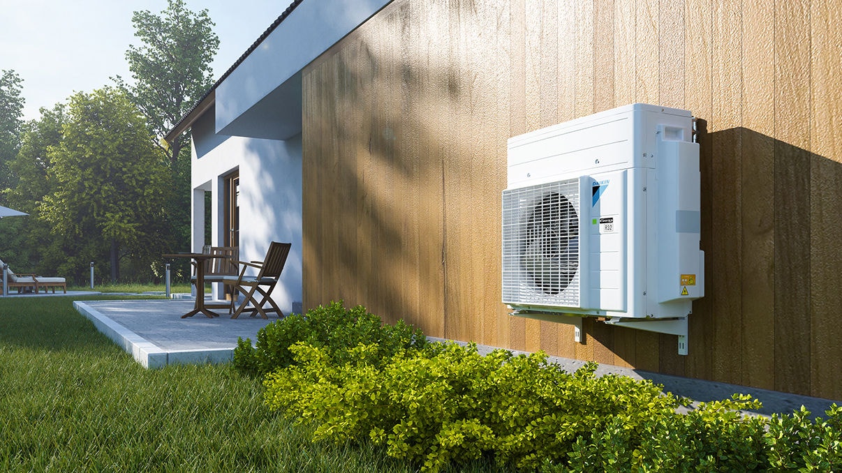 Udendørsenhed til varmepumpesystem installeret ved siden af en terrasse.