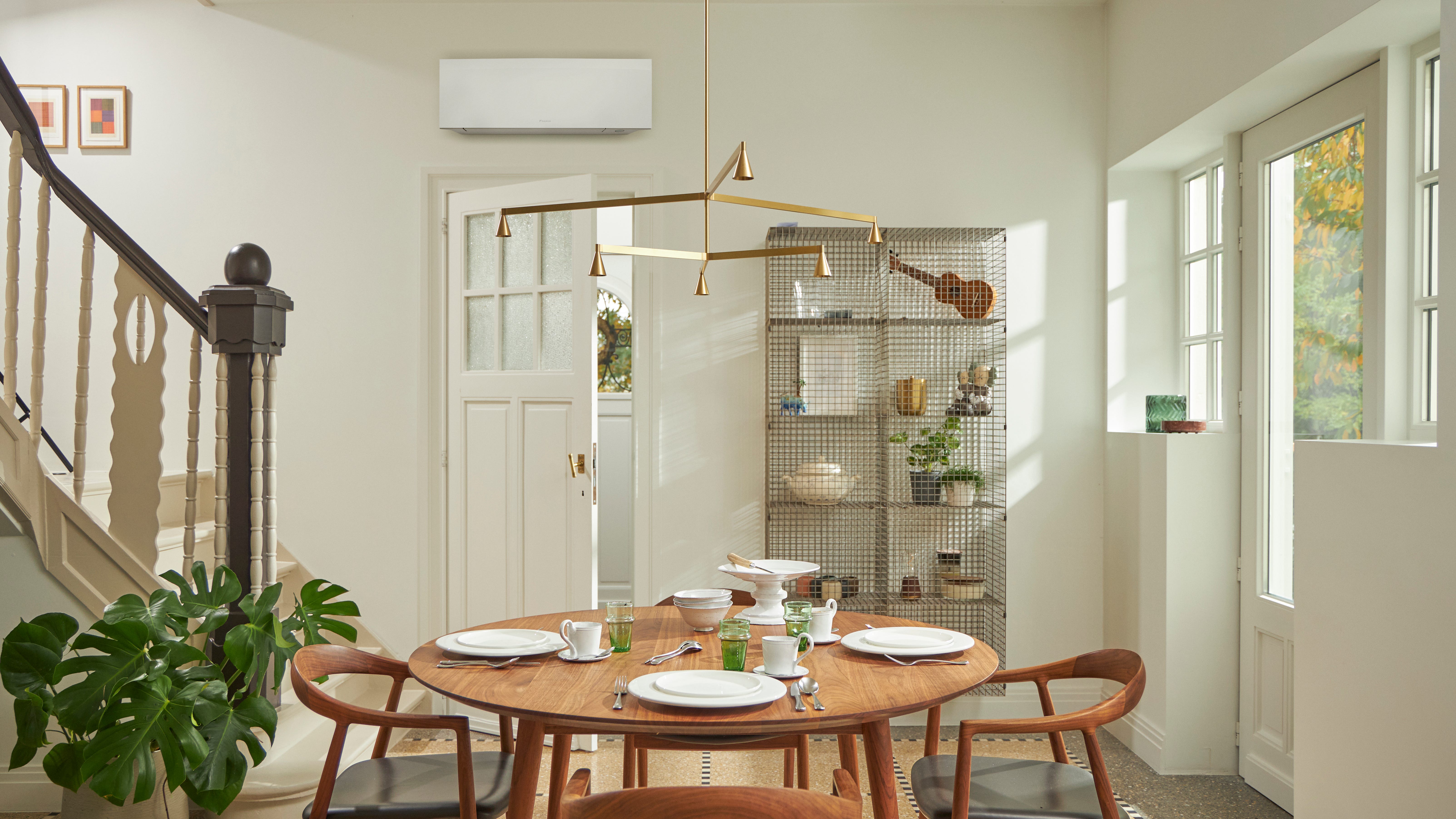 Izba s veľkým oknom, dreveným stolom a čiernou nástennou klimatizačnou jednotkou