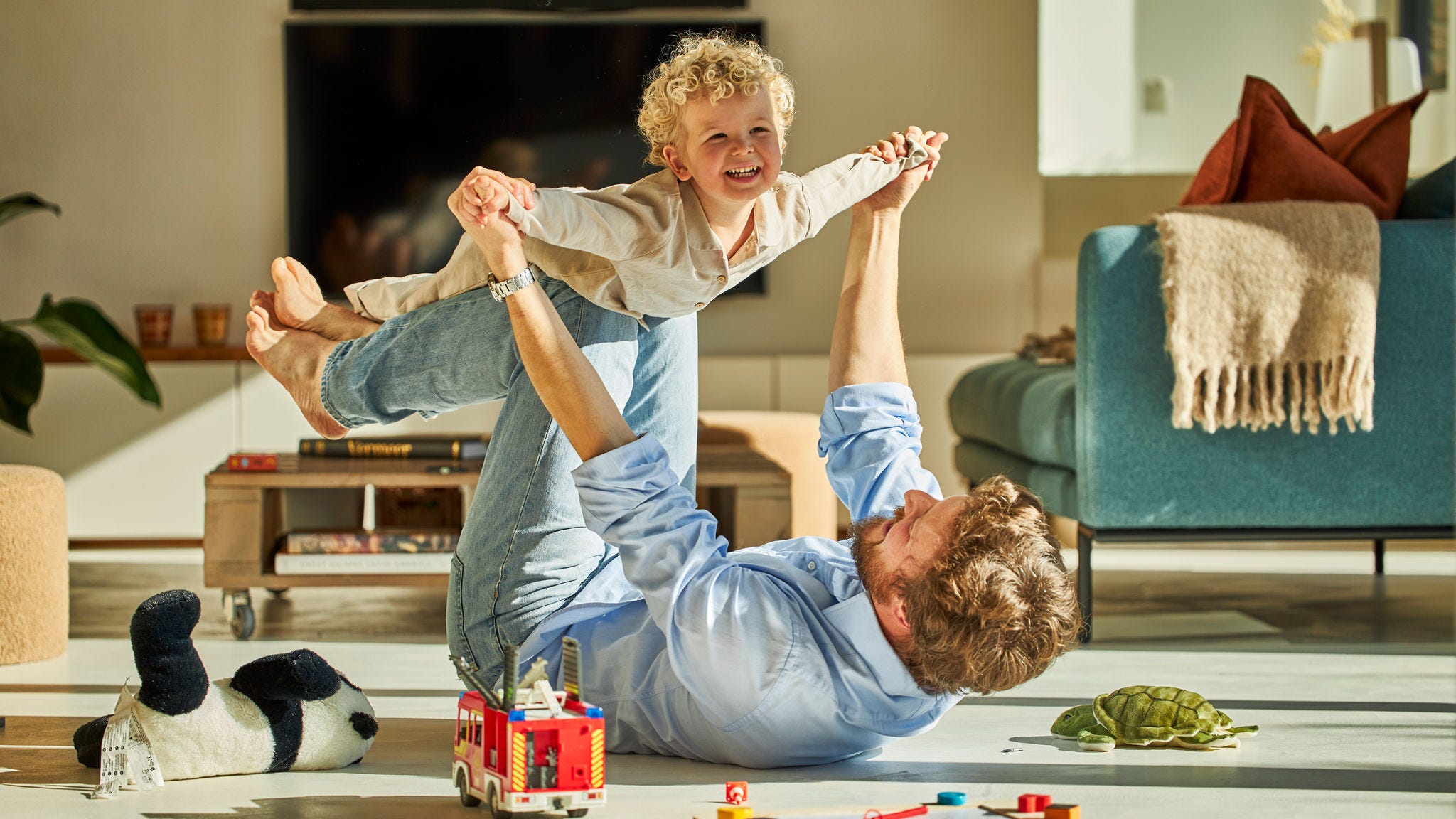 Otec a jeho dieťa sa spolu šťastne hrajú a užívajú si teplo podlahového kúrenia